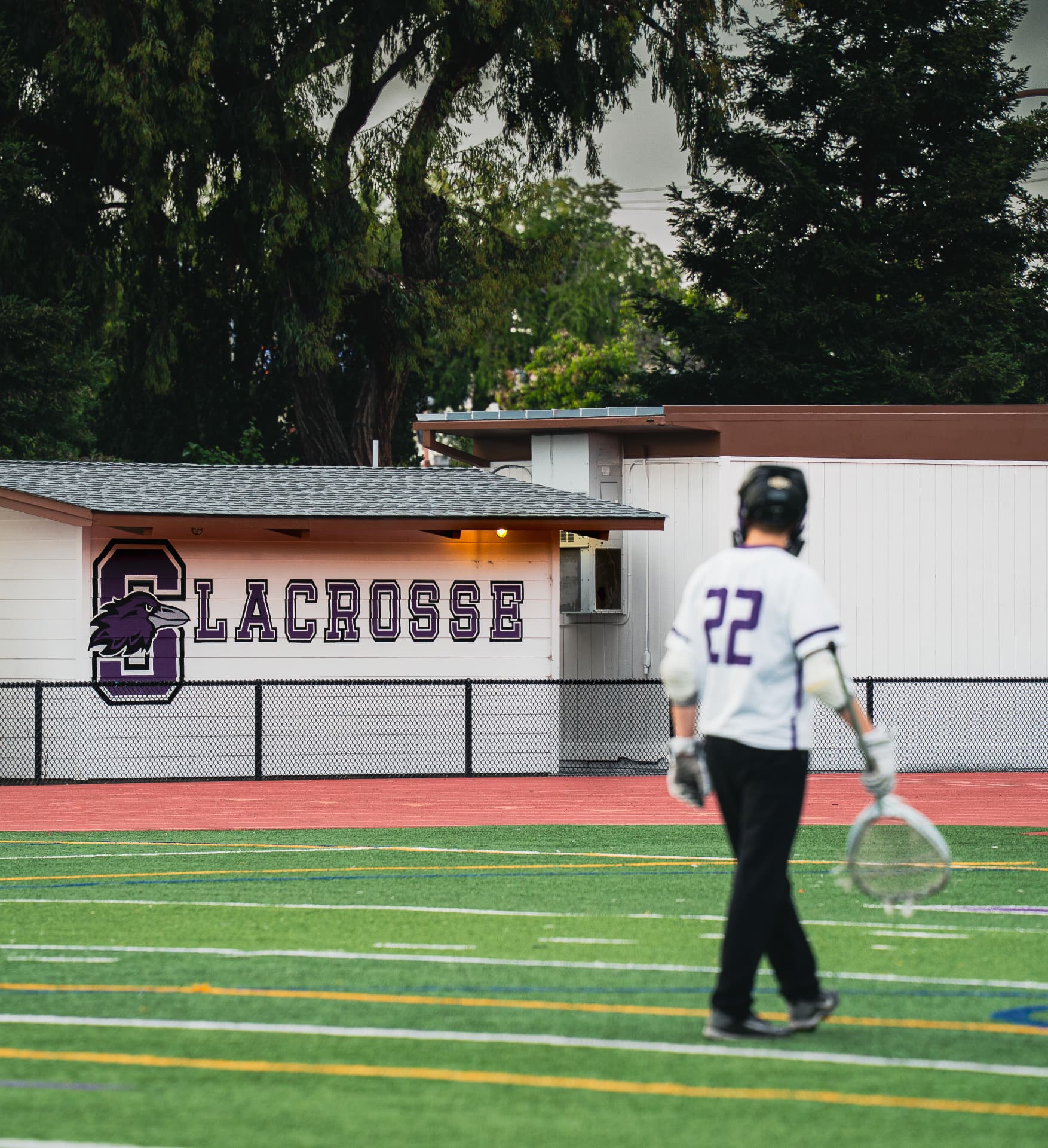 Lacrosse player walking off past the field house
